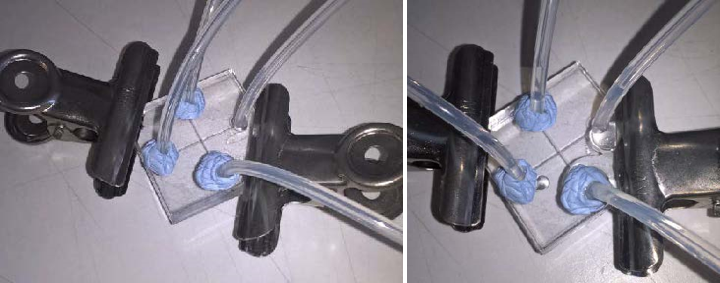 Figure 7: Prototype laser cut microfluidic chip held together by steel clamps. Showing attempt to seal wires with Bluetack (right) and the resulting leak (left).